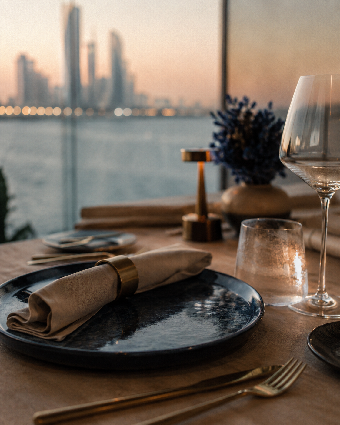 A deep blue place setting at dusk, the Abu Dhabi skyline behind it
