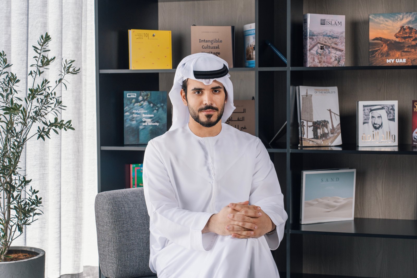 Tahnoon Alqubaisi, seated in a library in a white kandura