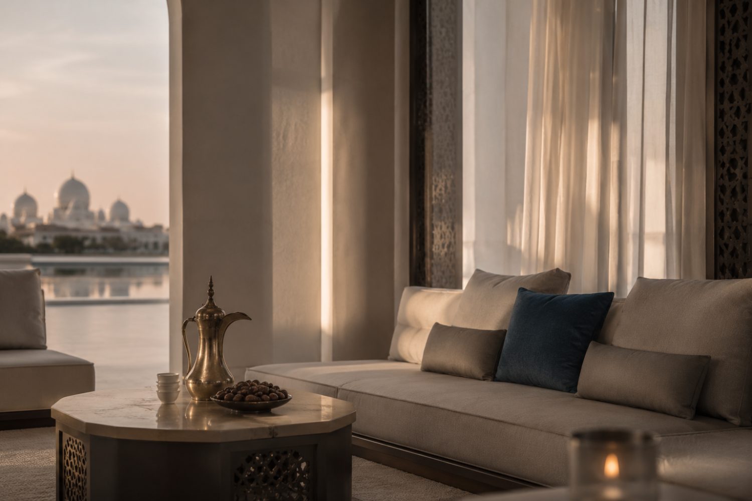 Abu Dhabi Blue — a contemporary majlis with a brass dallah and dates on a marble table, a deep-blue cushion, and a mosque on the water at dusk.